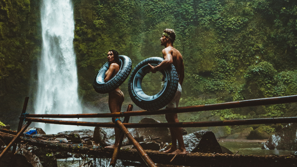 a couple storing water bottles under tires while they explore a waterfall 