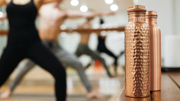 yoga practitioners practice the ayurveda experience with a copper bottle
